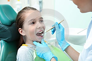 Professional dentist working with little patient in clinic
