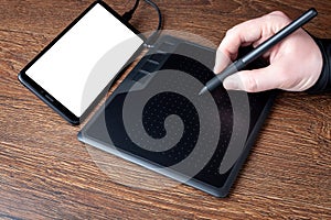 Professional designer using graphic tablet connected to smartphone with digital pen. Close up retouching photo. Blank screen.