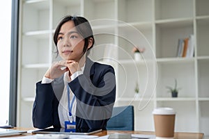 A professional and determined Asian businesswoman sits at her desk