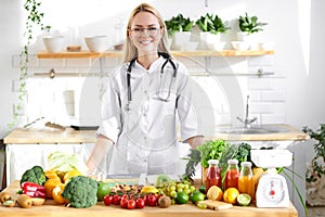 Professional dietitian in medical suit posing at camera, healthy food vegetables and fruits on table