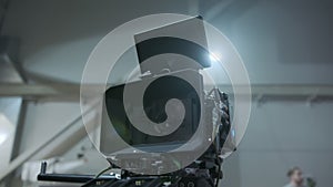 Professional digital cinema camera with set of light hanging in studio background. Close upmove camera footage