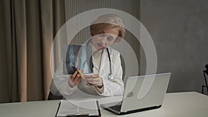 Professional Doctor Analyzing X-Ray During Online Consultation in Office Environment