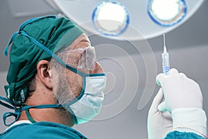 Professional doctor holding general anesthetic medicine or antiviral drug vaccine needle syringe for patient before surgery in the