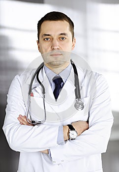 Professional doctor with a stethoscope is standing with crossed arms in a clinic. Perfect medical service in hospital