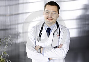 Professional doctor with a stethoscope is standing with crossed arms in a clinic. Perfect medical service in hospital