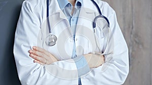 Professional doctor in white coat with stethoscope standing with arms crossed. Unrecognizable woman physician is ready