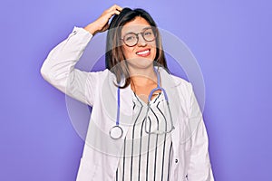 Professional doctor woman wearing stethoscope and medical coat over purple background confuse and wonder about question