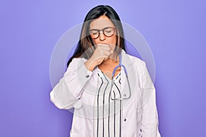 Professional doctor woman wearing stethoscope and medical coat over purple background feeling unwell and coughing as symptom for