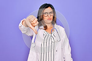 Professional doctor woman wearing stethoscope and medical coat over purple background looking unhappy and angry showing rejection