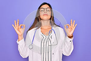 Professional doctor woman wearing stethoscope and medical coat over purple background relax and smiling with eyes closed doing