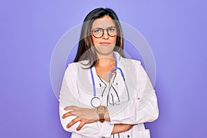 Professional doctor woman wearing stethoscope and medical coat over purple background skeptic and nervous, disapproving expression