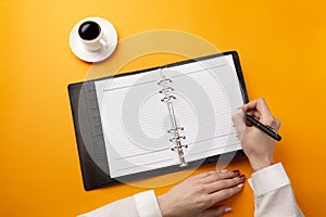 Professional doctor writing medical records in a notebook with coffee cup