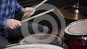 Professional drummer is hitting drum cymbals with drumsticks, close up. Rock musician is performing solo on drums on stage in reco