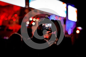 Professional dslr camera at music concert in raised up hand recording singer on a stage