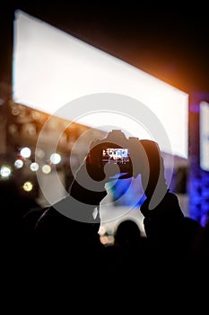 Professional dslr camera at music concert in raised up hand recording singer on a stage