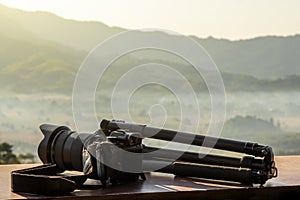 A professional DSLR camera and tripod in the nature for background