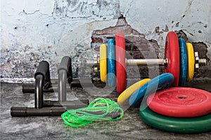 Professional dumbbells, multi-colored weight plates, jump rope and push-up stops on a vintage background. Sports equipment.