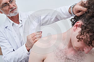 Professional elderly doctor putting tapes on the neck of sportswoman during kinesiotherapy
