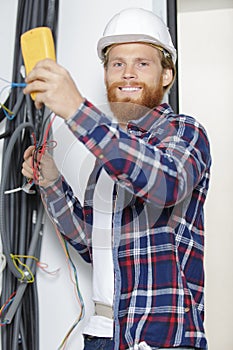 professional electrician with helmet repairs cable connections