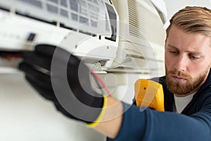 professional electrician man fixing heavy air conditioner