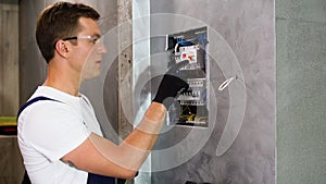 Professional electrician sets up electricity in the apartment. Electrician repairing electrical box and using