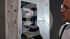 Professional electrician sets up electricity in the apartment. Electrician repairing electrical box and using