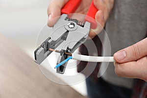 Professional electrician stripping wiring indoors, closeup view