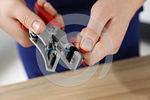 Professional electrician stripping wiring at table, closeup