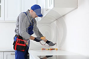 Professional electrician with tester checking voltage indoors