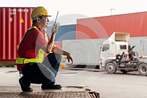 Professional engineer container cargo foreman in helmets working sitting and using walkie talkie checking stock into container for