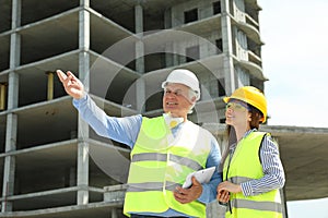 Professional engineer and foreman with tablet in safety equipment