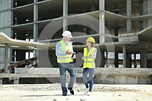 Professional engineer and foreman with tablet in safety equipment