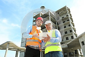 Professional engineer with tablet and foreman in equipment at construction site