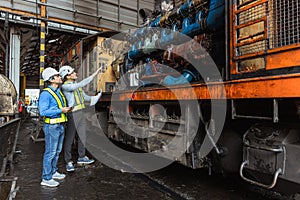 Professional engineer worker looking at old grease oil dirty large locomotive engine plan to overhaul service. diesel train