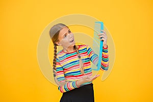 Professional equipment. Combing hair. Cheerful happy smiling little kid with giant comb. Comb for tangled hair