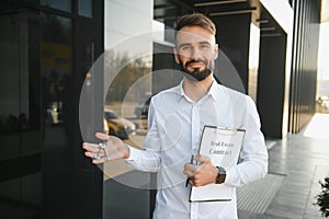 Professional estate seller with clipboard writing documents outside in front of rented house with advertising area