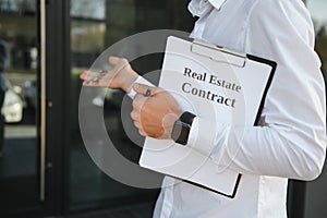 Professional estate seller with clipboard writing documents outside in front of rented house with advertising area