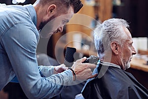 Professional experienced barber working with hair cutting machine