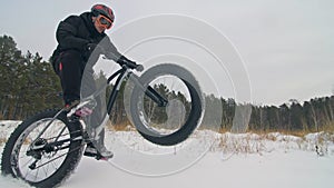 Professional extreme sportsman biker riding fat bike in outdoor. Cyclist ride in winter snow forest. Man does trial