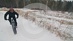 Professional extreme sportsman biker riding fat bike in outdoor. Cyclist ride in winter snow forest. Man does trial