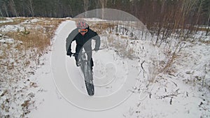 Professional extreme sportsman biker riding fat bike in outdoor. Cyclist ride in winter snow forest. Man does trial
