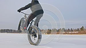 Professional extreme sportsman biker riding fat bike in outdoor. Cyclist ride in winter snow forest. Man does trial