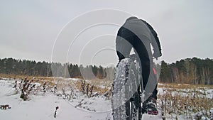 Professional extreme sportsman biker riding fat bike in outdoors. Cyclist ride in winter in snow field, forest. Man does