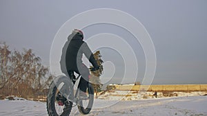 Professional extreme sportsman biker riding fat bike in outdoors. Cyclist ride in winter in snow field, forest. Man does