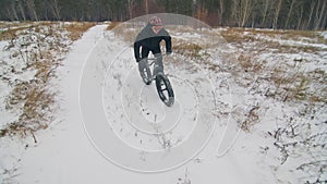 Professional extreme sportsman biker riding fat bike in outdoors. Cyclist ride in winter in snow field, forest. Man does