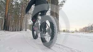 Professional extreme sportsman biker riding fat bike in outdoors. Cyclist ride in winter in snow field, forest. Man does