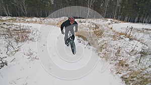 Professional extreme sportsman biker riding fat bike in outdoors. Cyclist ride in winter in snow field, forest. Man does