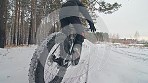 Professional extreme sportsman biker riding a fat bike in outdoors. Cyclist ride in the winter snow forest. Man does