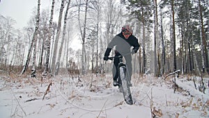 Professional extreme sportsman biker riding a fat bike in outdoors. Cyclist ride in the winter snow forest. Man does