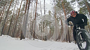 Professional extreme sportsman biker riding a fat bike in outdoors. Cyclist ride in the winter snow forest. Man does